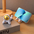 Astronaut figure phone stand holding a smartphone