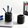 Black tire-shaped pencil holders on a desk