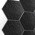 Black hexagon acoustic wall panels mounted on a wall, close-up of felt texture